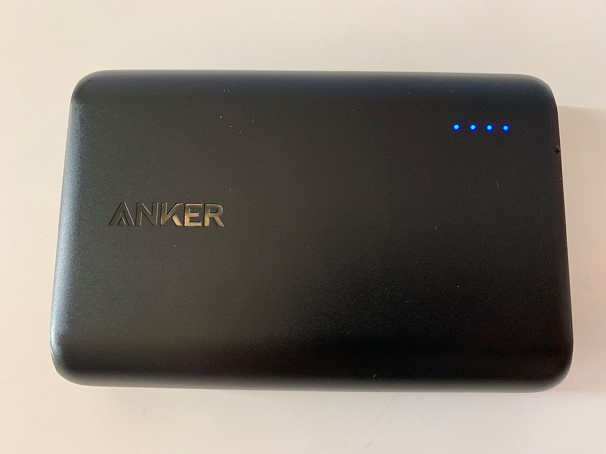A black Anker PowerCore 10000 power bank with four blue charge lights lit