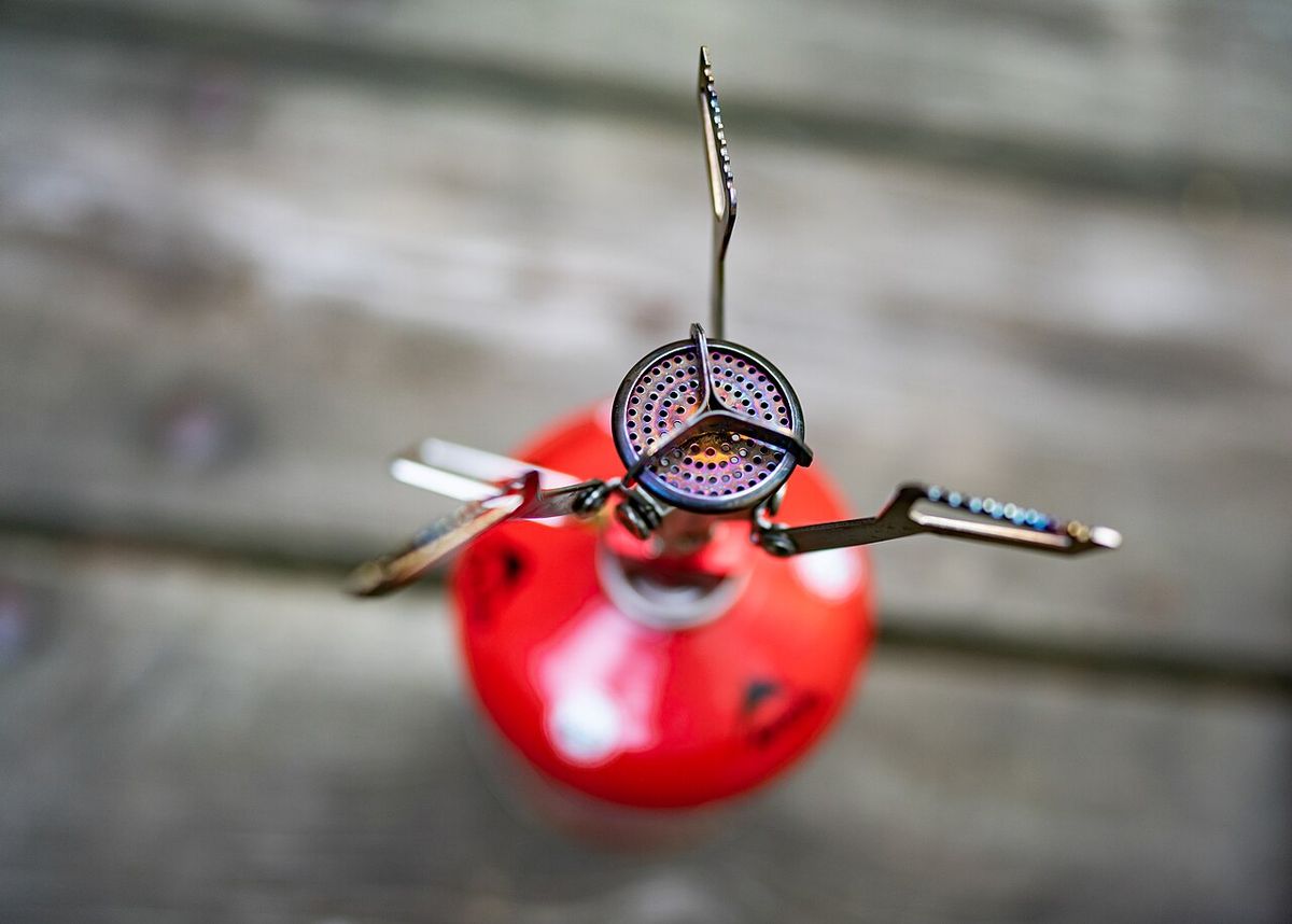An MSR PocketRocket canister stove with its serrated pot supports folded out, seen from above on a red fuel canister