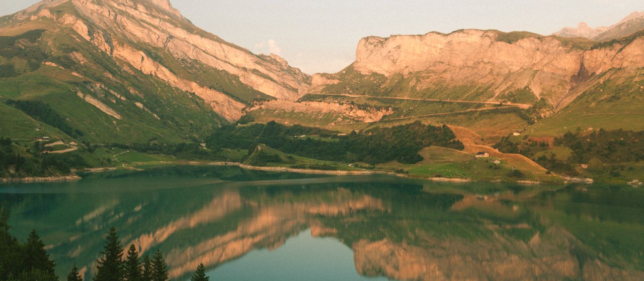 Evening light on cliffs above Roselend Lake, reflected in still water